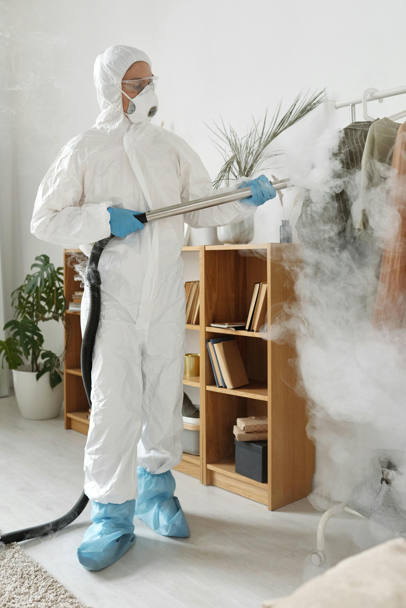 Protective-suit technician disinfecting clothing and surrounding contents