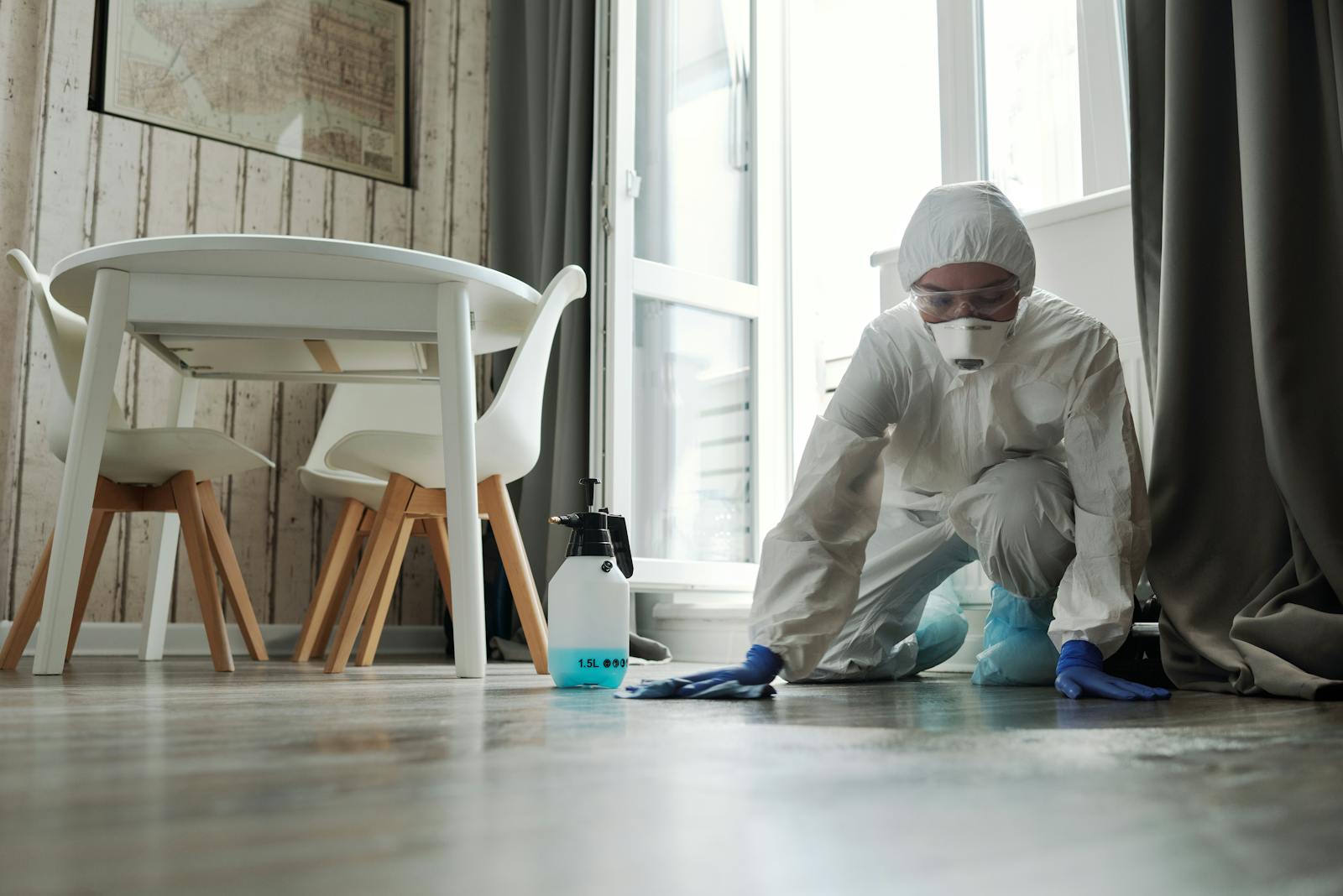 Protective-suit cleaner wiping a floor during specialized cleanup